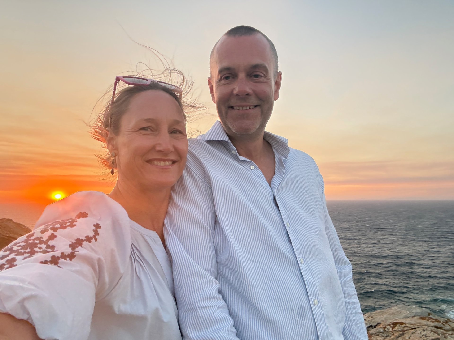 Johanne Taugbøl and Øystein Tynning on the rocky Akri House site at sunset, with the Aegean Sea behind them.